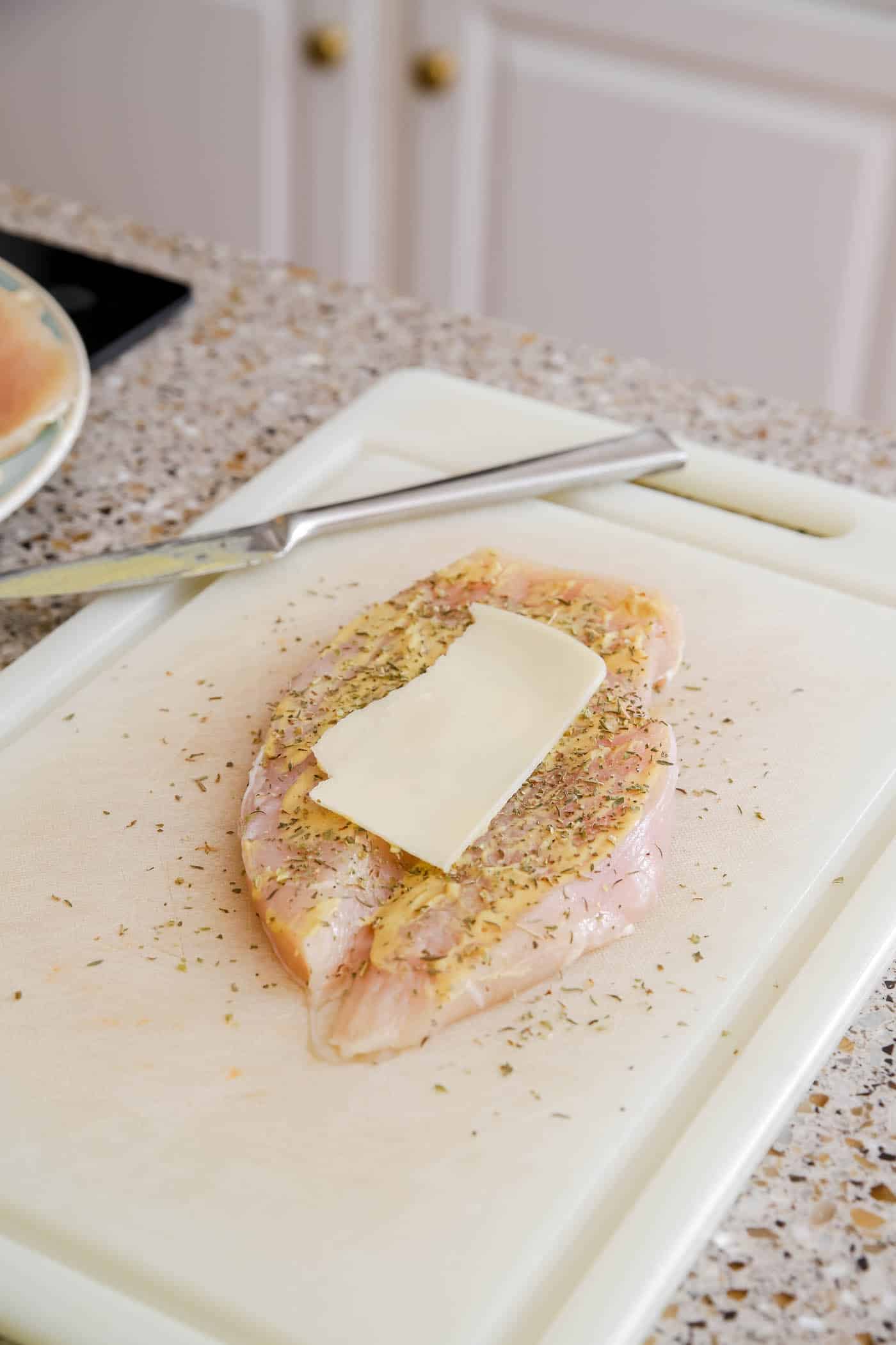 Layers of cheese, mustard and spices on flattened chicken