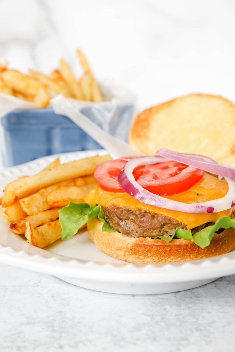 homemade burger with French fries and toppings like lettuce, cheese and tomato.