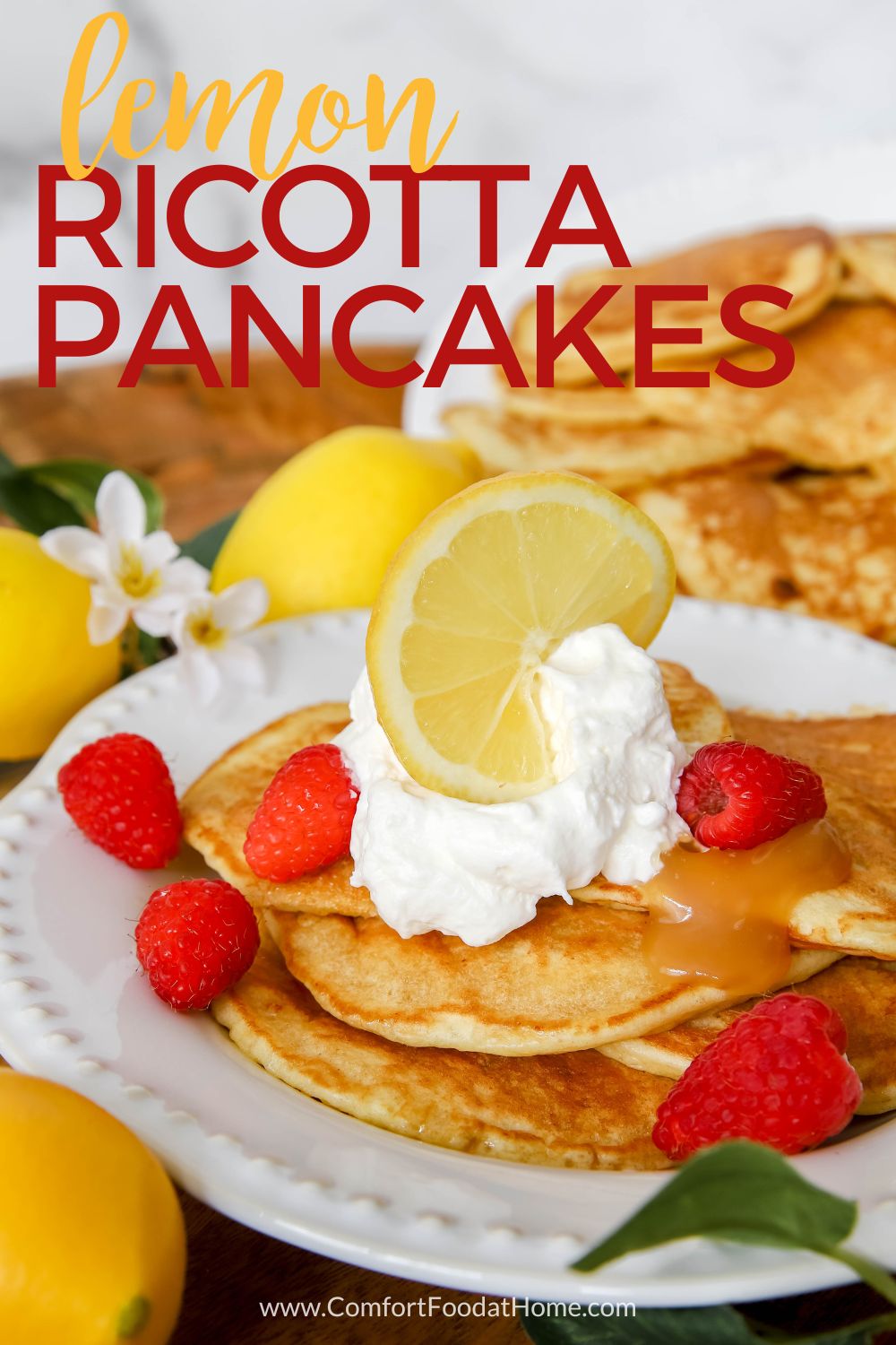lemon ricotta pancakes with lemon slices and raspberries on top.