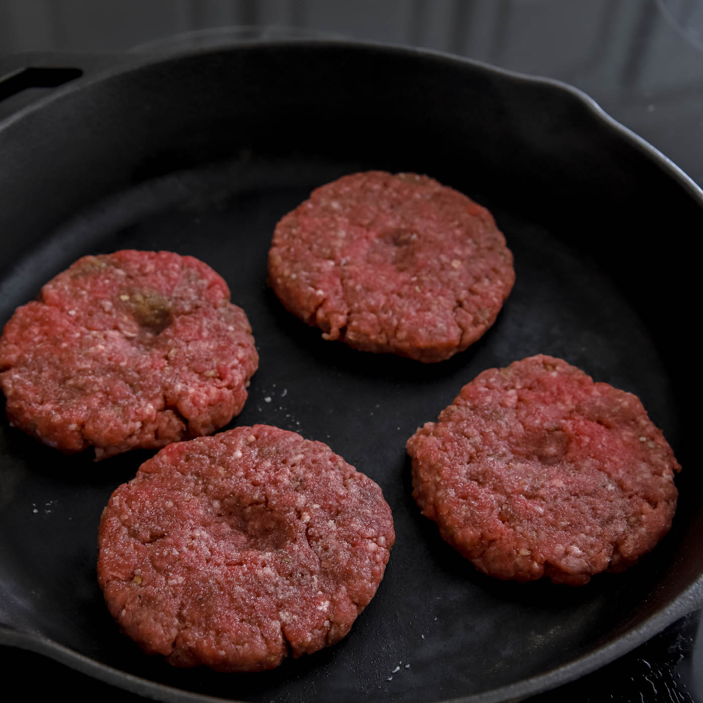 hamburgers formed into patties in a cast iron skillet