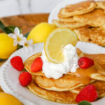 lemon ricotta pancakes with lemon curd and whipped cream on top.