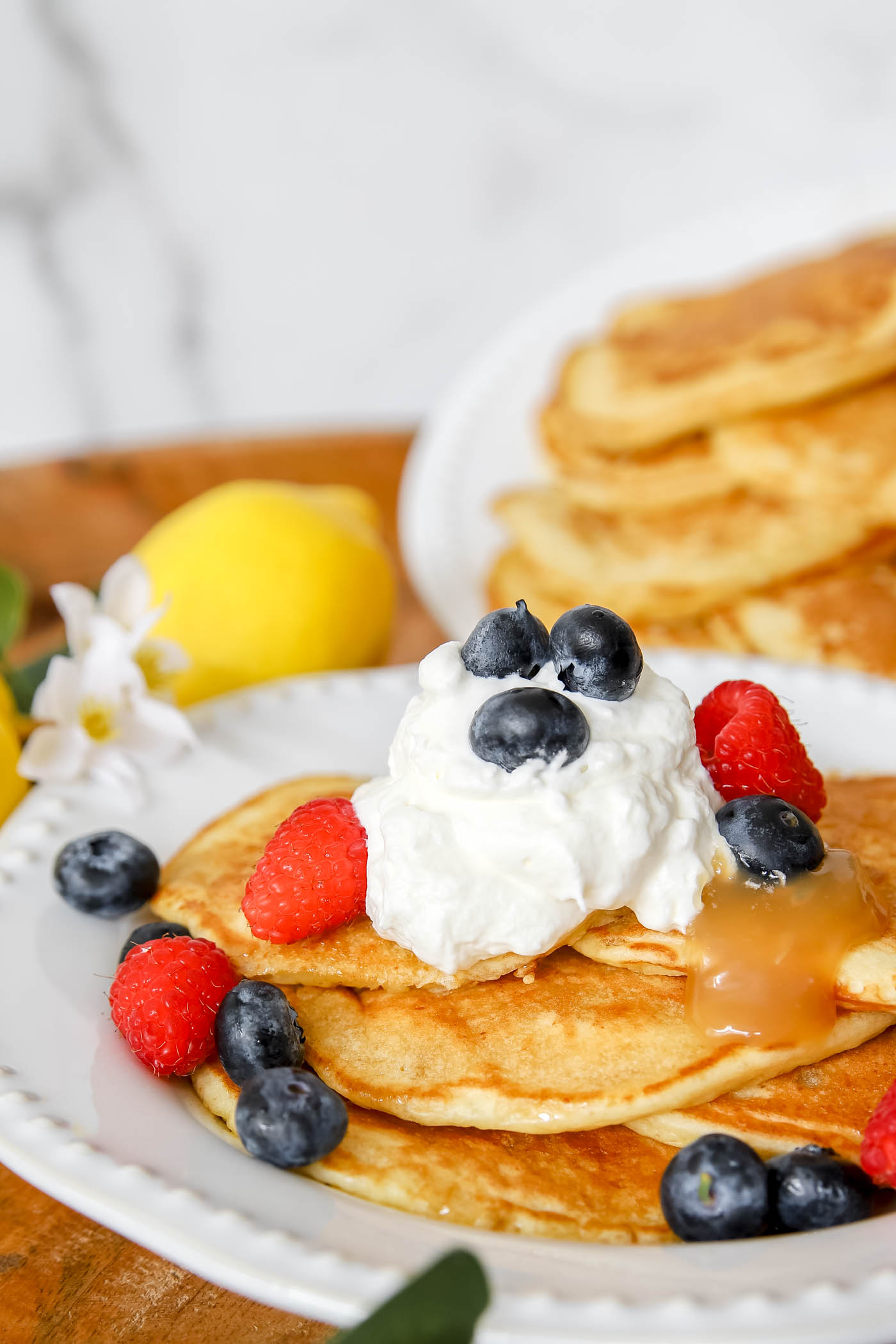 lemon ricotta pancakes with blueberries, raspberries, whipped cream and lemon curd toppings.