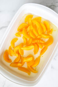 peaches with the juice in a baking dish.