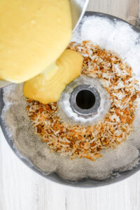 coconut rum bundt cake batter being poured into a bundt cake pan.