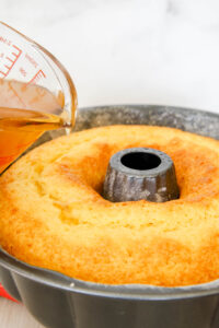 Pouring glaze on coconut rum Bundt cake.