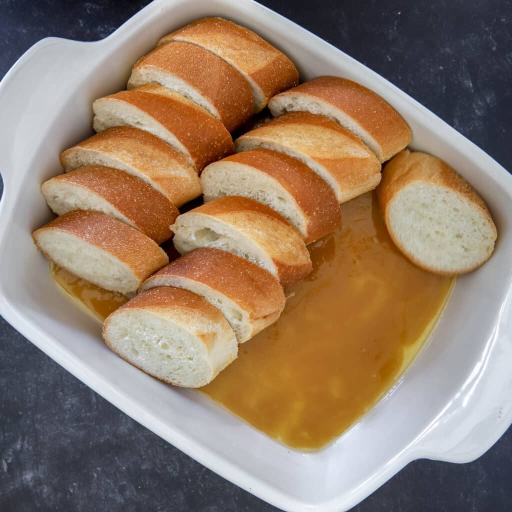layered slices of French bread in butter and sugar mixture for French toast casserole.