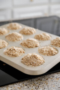 press the topping on to the top of the apple crisp muffins with streusel topping.