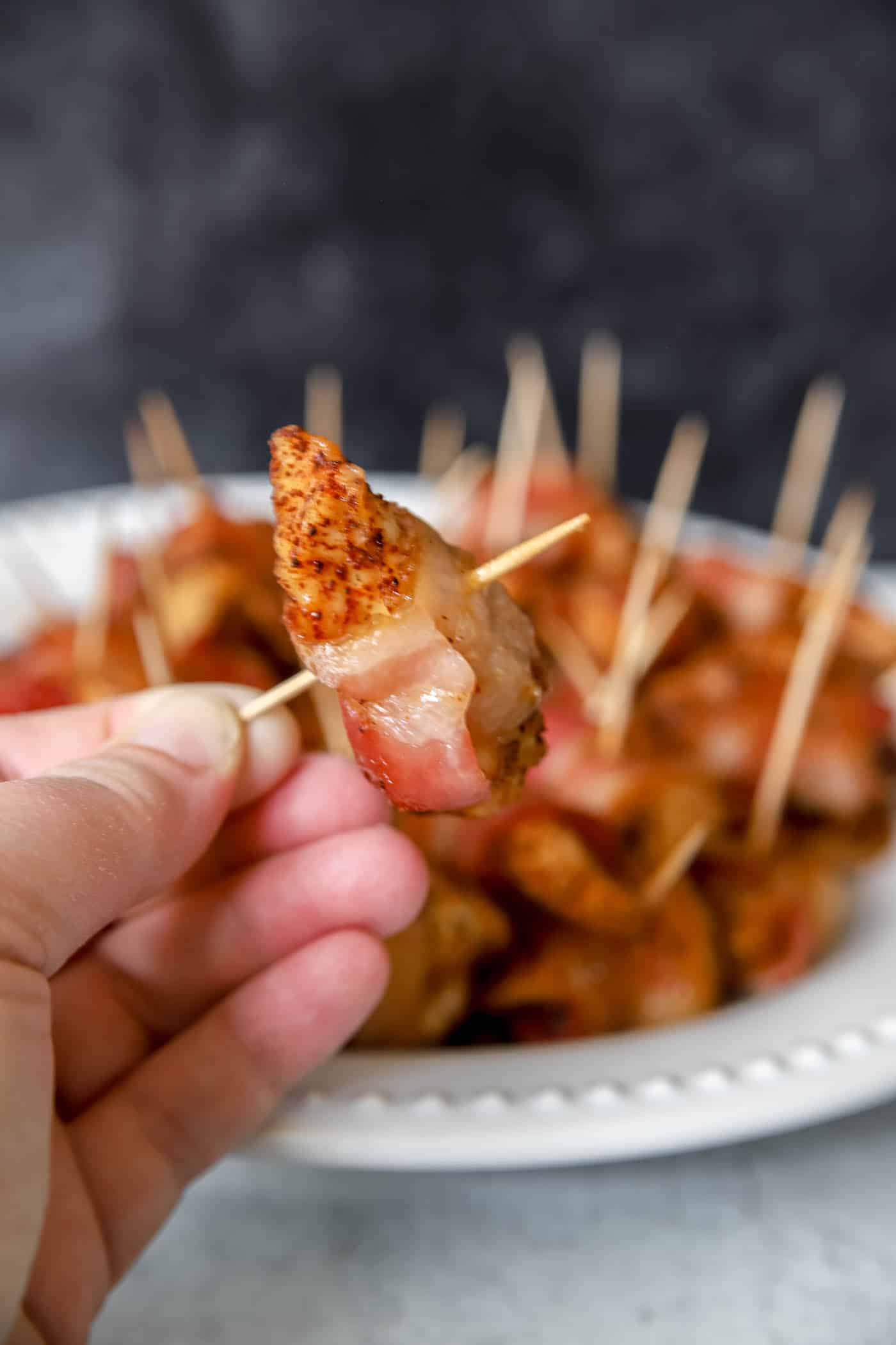 bacon-wrapped chicken bite held up by a hand.