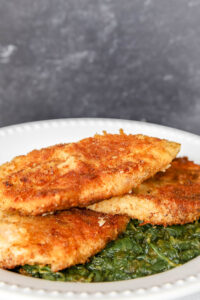 paremsan-crusted chicken on a bed of spinach