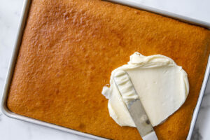 spreading the icing onto pumpkin bars.