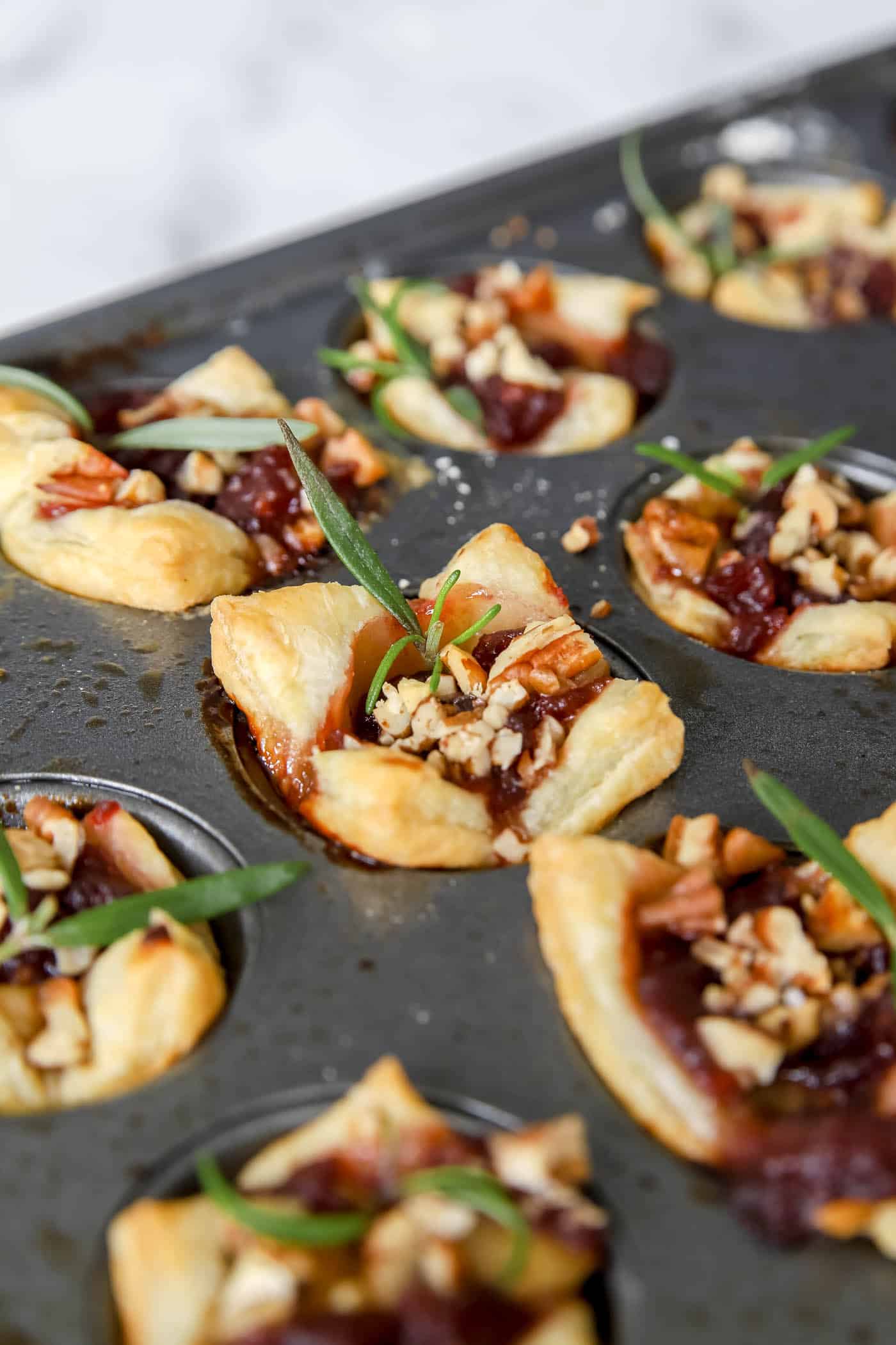 fresh rosemary garnish on cranberry brie bites.