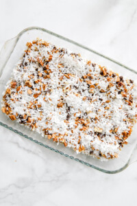layers of hello dolly bars over graham cracker crust.