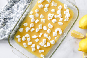 cream cheese cubes layered over lemon curd in baking dish for lemon dump cake.