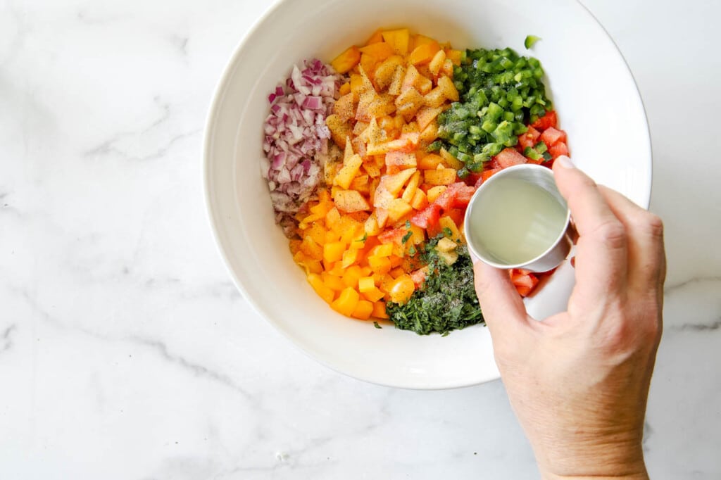 peach salsa in a bowl with lime juice.