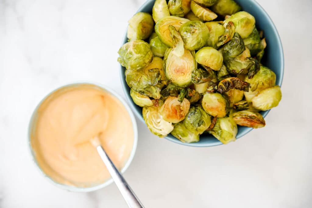 roasted Brussels sprouts on a sheet pan with sriracha mayo sauce.