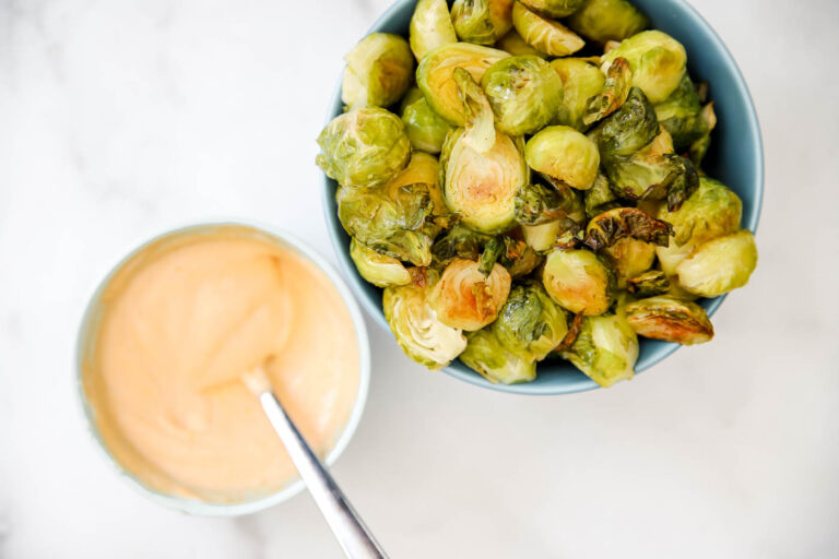 roasted Brussels sprouts on a sheet pan with sriracha mayo sauce.