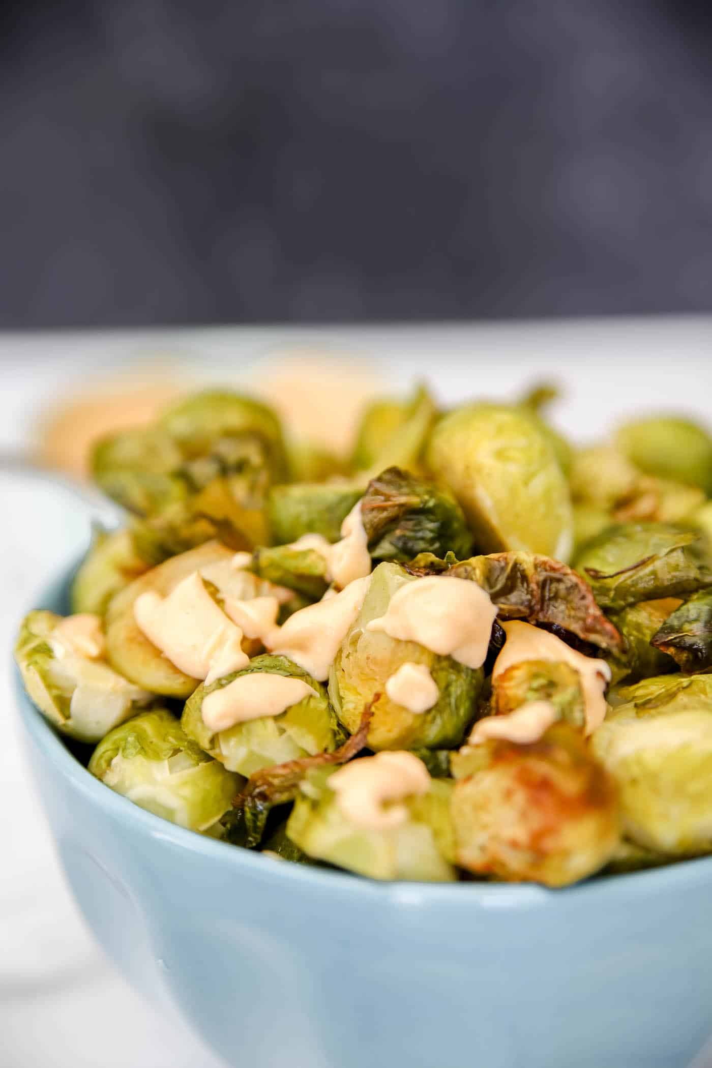 roasted Brussels sprouts on a sheet pan with sriracha mayo sauce.