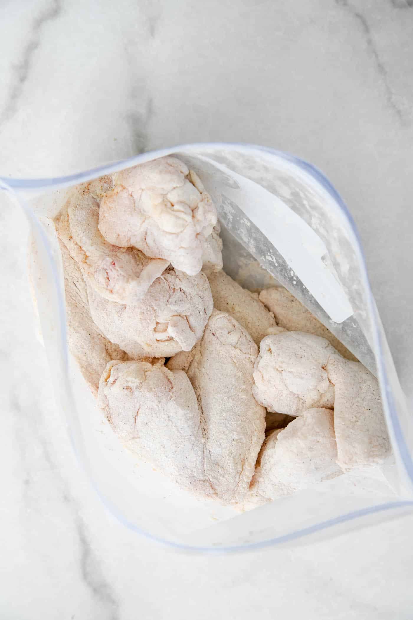 Raw chicken wings in a ziplock bag bag with dry rub for bbq chicken.