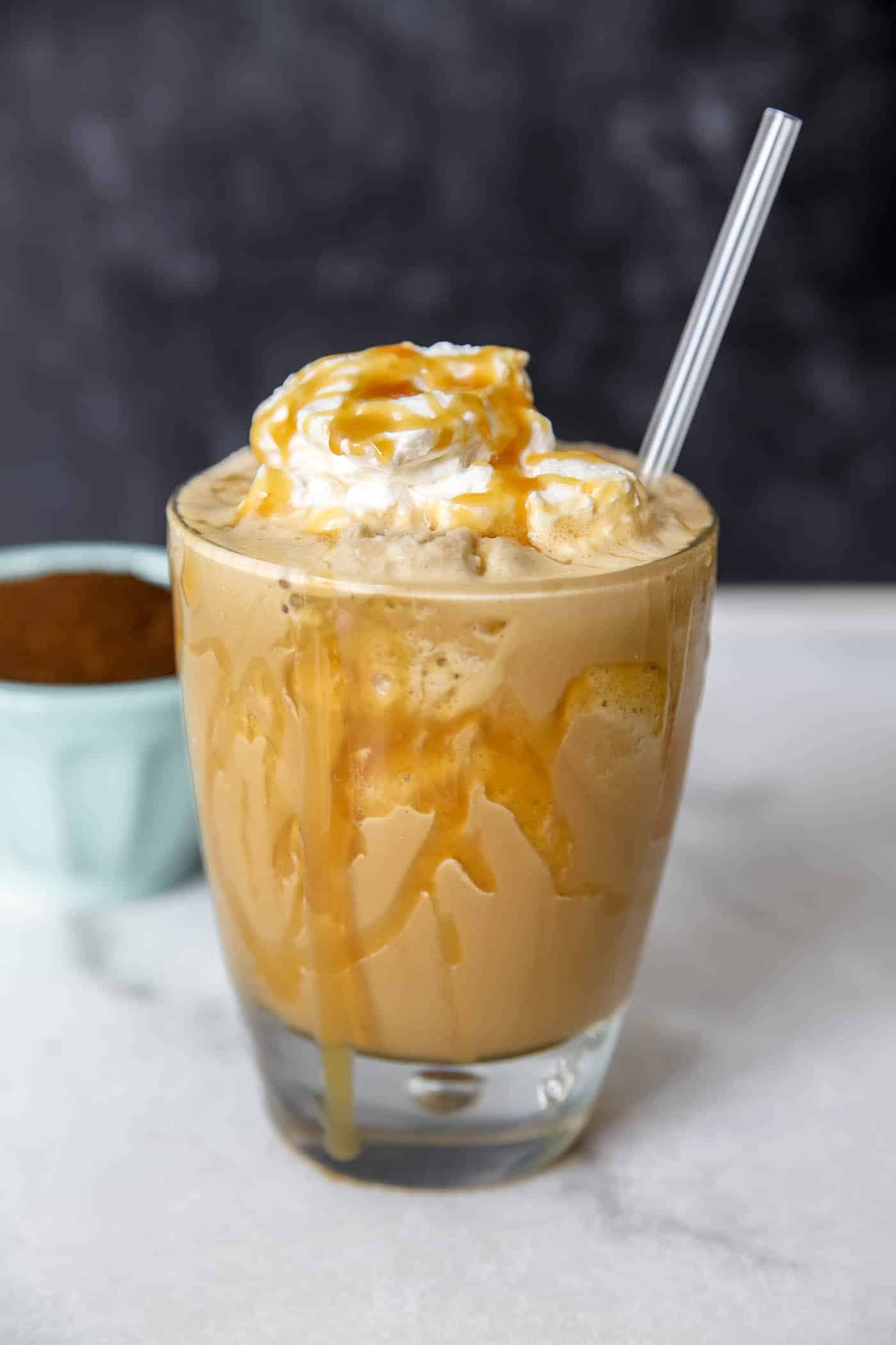 frosted coffee in a glass cup with caramel syrup drizzle.