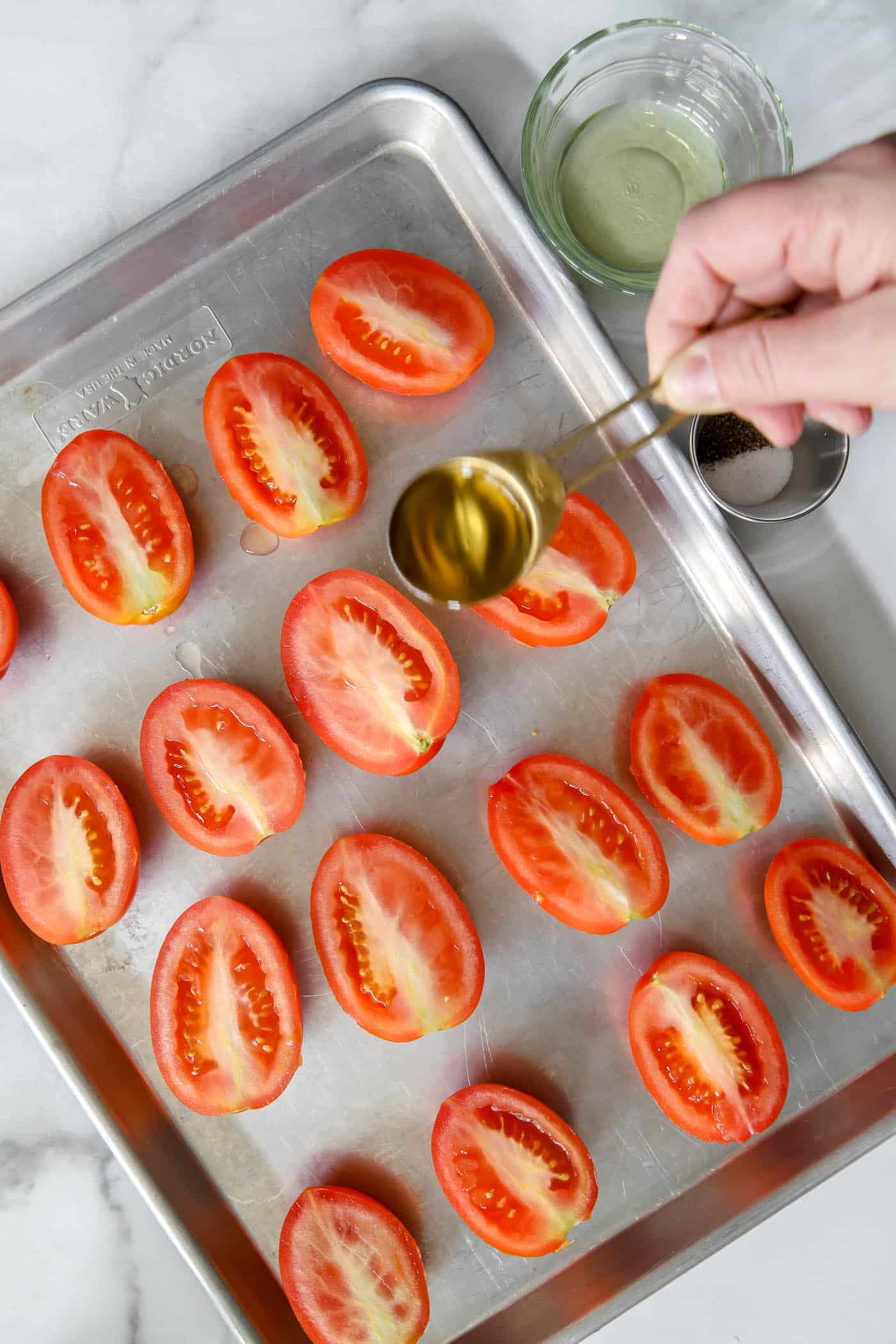 tomatoes on a roasting pan with drizzle of olive oil.